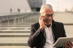 Image of man on phone looking at tablet.