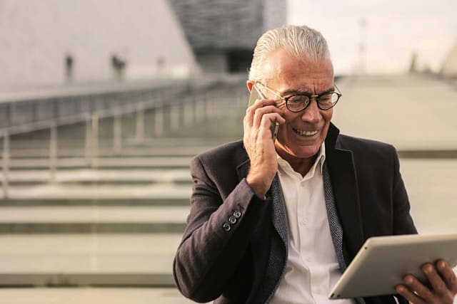 Image of man on phone looking at tablet.